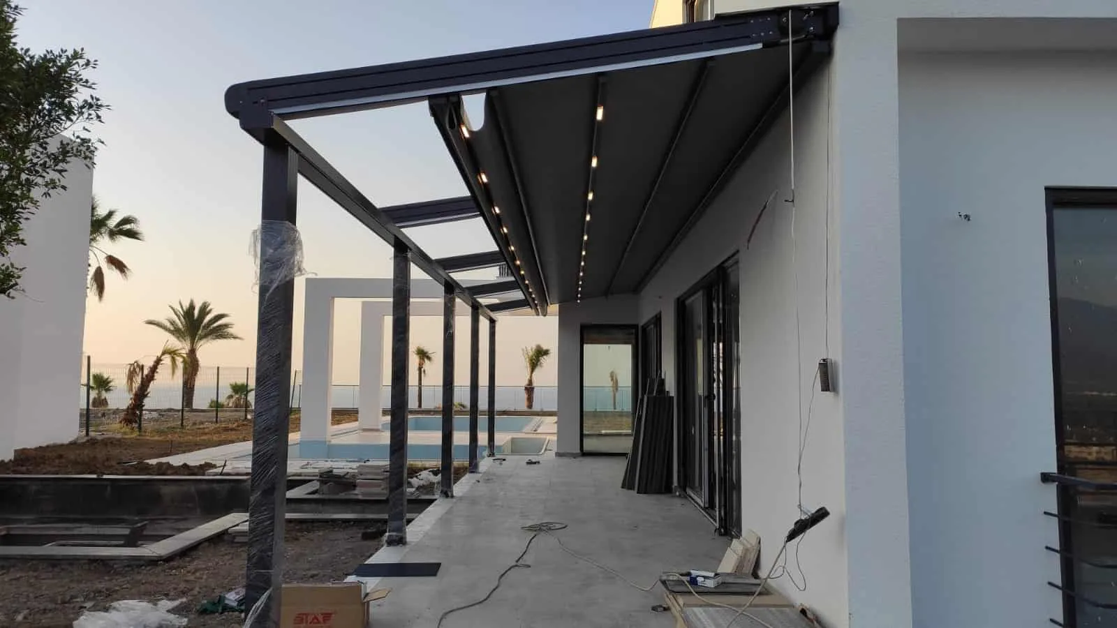 Gün batımında deniz kenarındaki bir yapıya uygulanmış pergola geçiş alanı