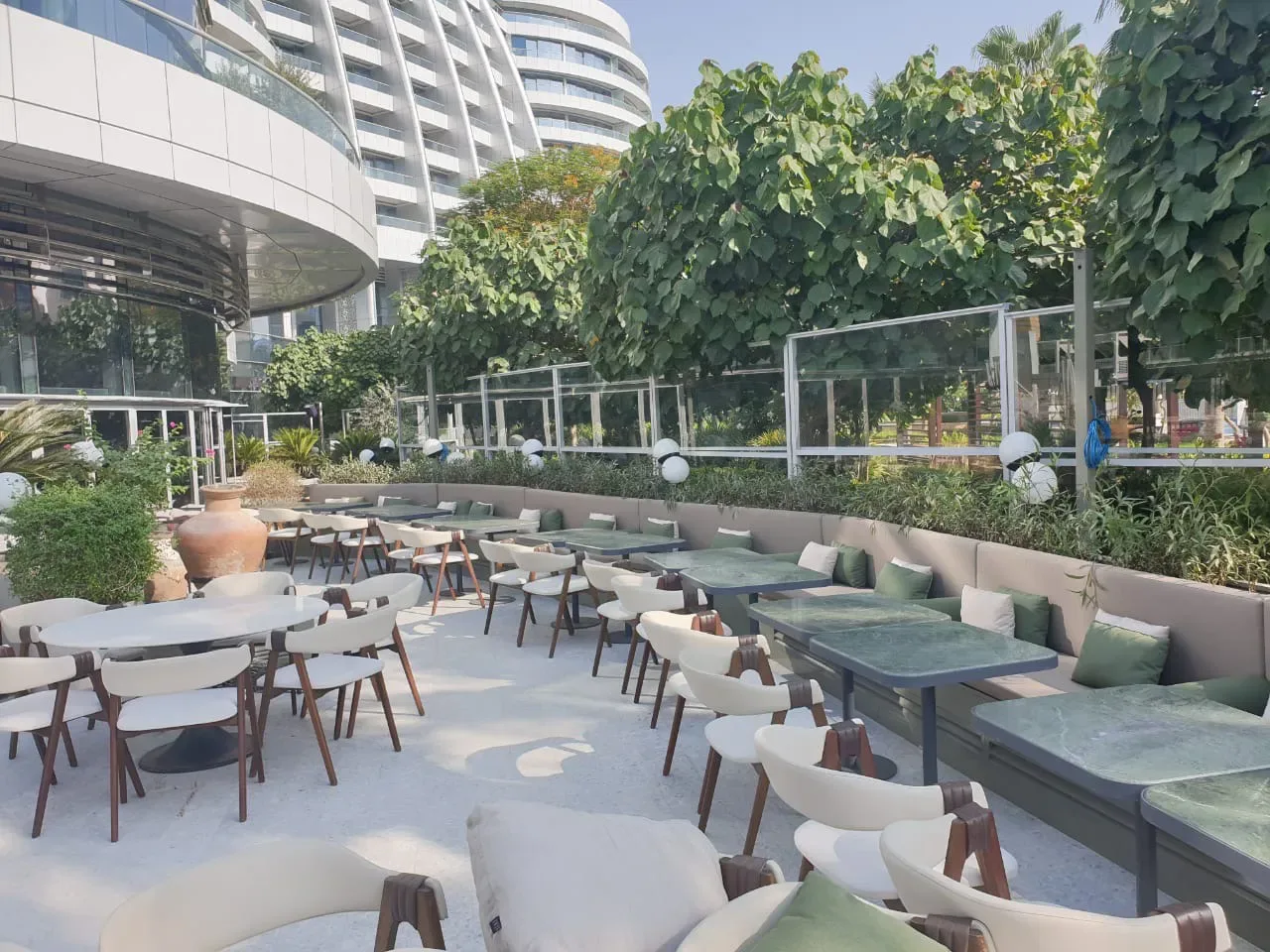 Geniş bir restoran terasında masaları çevreleyen rüzgâr kırıcı düzeni